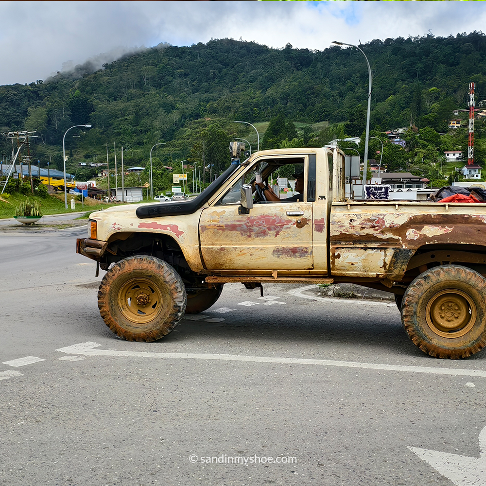 A white rustic car stopped at an intersection in Kundasang.